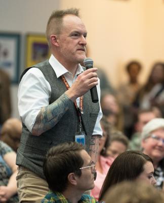 Conference attendee holds a microphone and asks a question.
