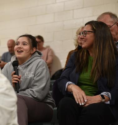 Conference attendee holds a microphone and asks a question.
