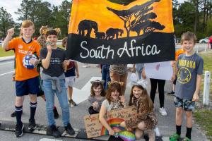Elementary School students pose with a flag they painted with elephants, trees and the words “South Africa.”