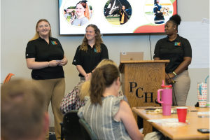 Three Perquimans High School students smile while giving a presentation.