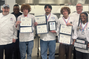 Students in chef’s uniforms pose with winners’ plaques and certificates.