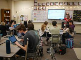  Members of The Green Hope Falcon’s staff gather for an editorial meeting. One student is pointing at the smart board while speaking.