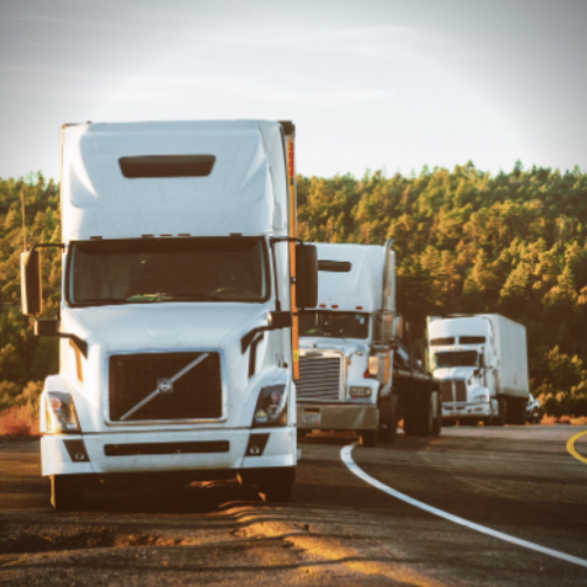 A line of semi trucks driving on the highway
