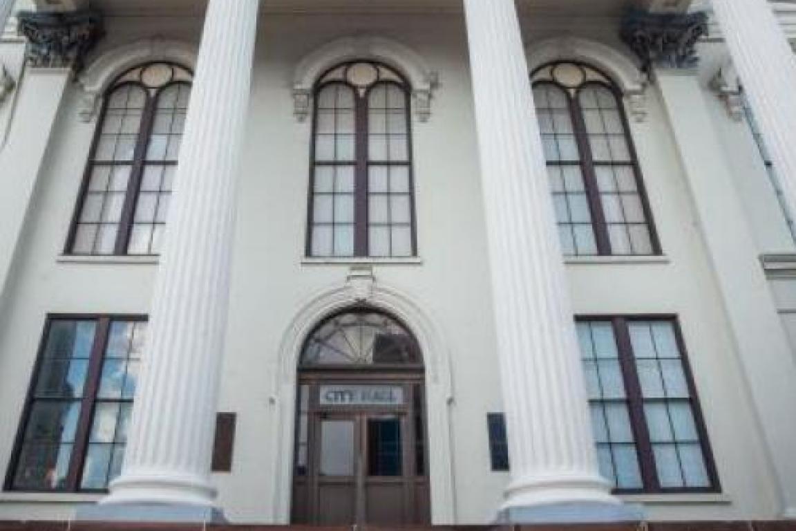 exterior of white courthouse with tall columns and arched door
