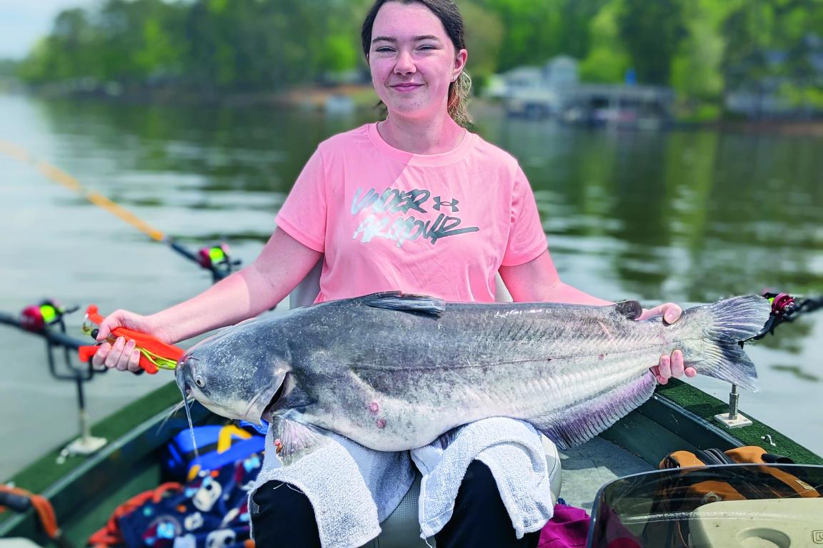 Angler holds a large blue catfish across her lap