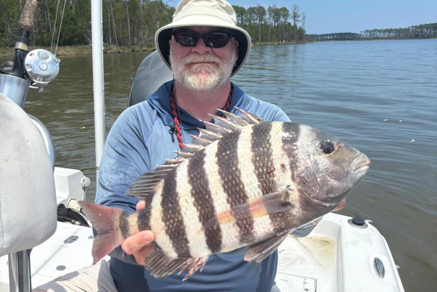Ben Ricks holds a Sheepshead fish while sitting in a boat