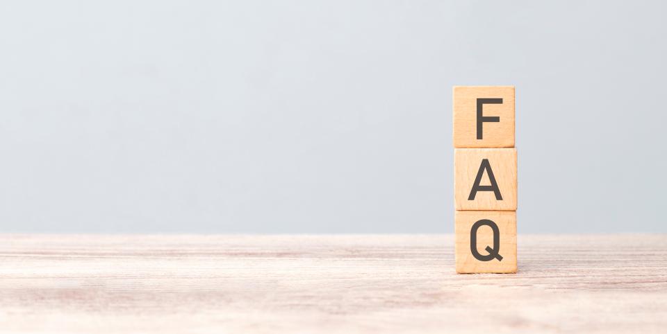 Three Scrabble letter tiles stacked on a desktop from top to bottom spelling out FAQ