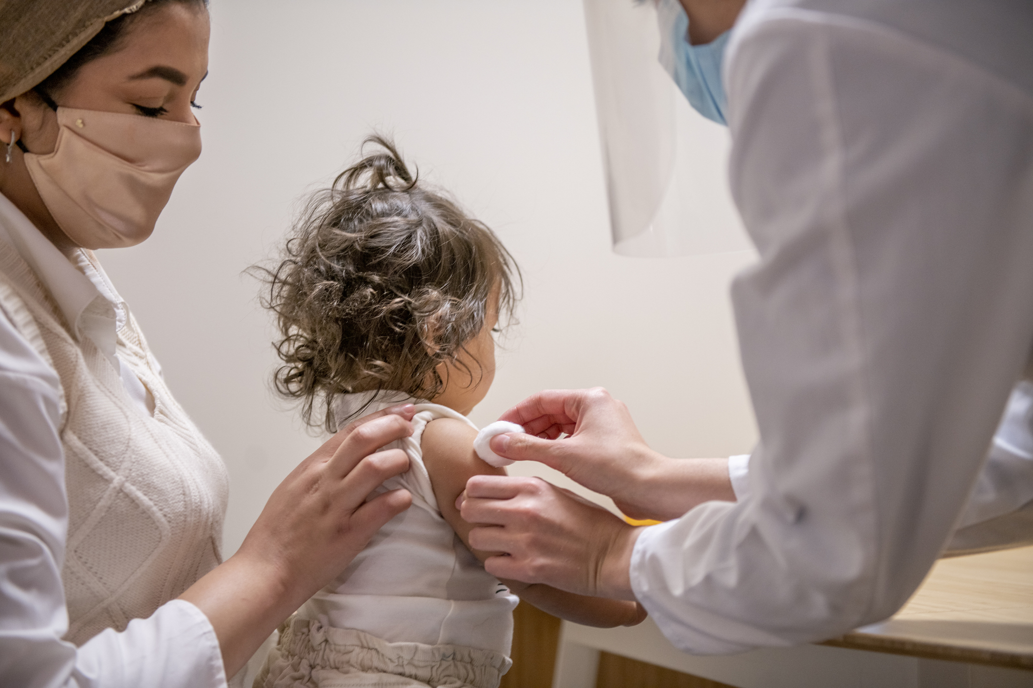 Mother holding toddler daughter being vaccinated