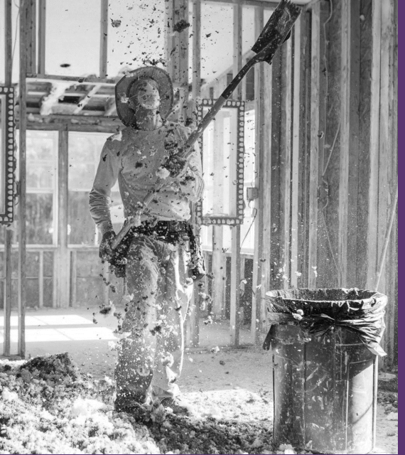 Person in protective gear painting or cleaning a wall