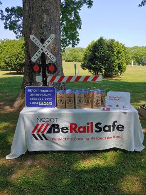 Be Rail Safe display table with railroad crossing sign at an outdoor public outreach event