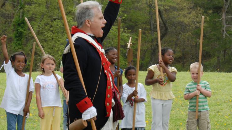 A Revolutionary War re-enactor cheers with kids A Revolutionary War re-enactor cheers with kids