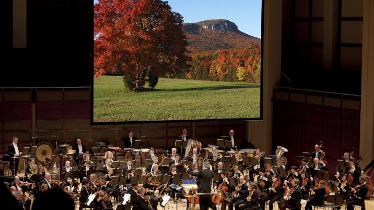 The North Carolina Symphony performs with an image of nature in the background The North Carolina Symphony performs with an image of nature in the background