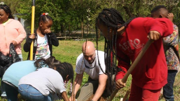 Students plant an apple tree sapling