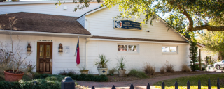 a white building with trees and a brown door during the day