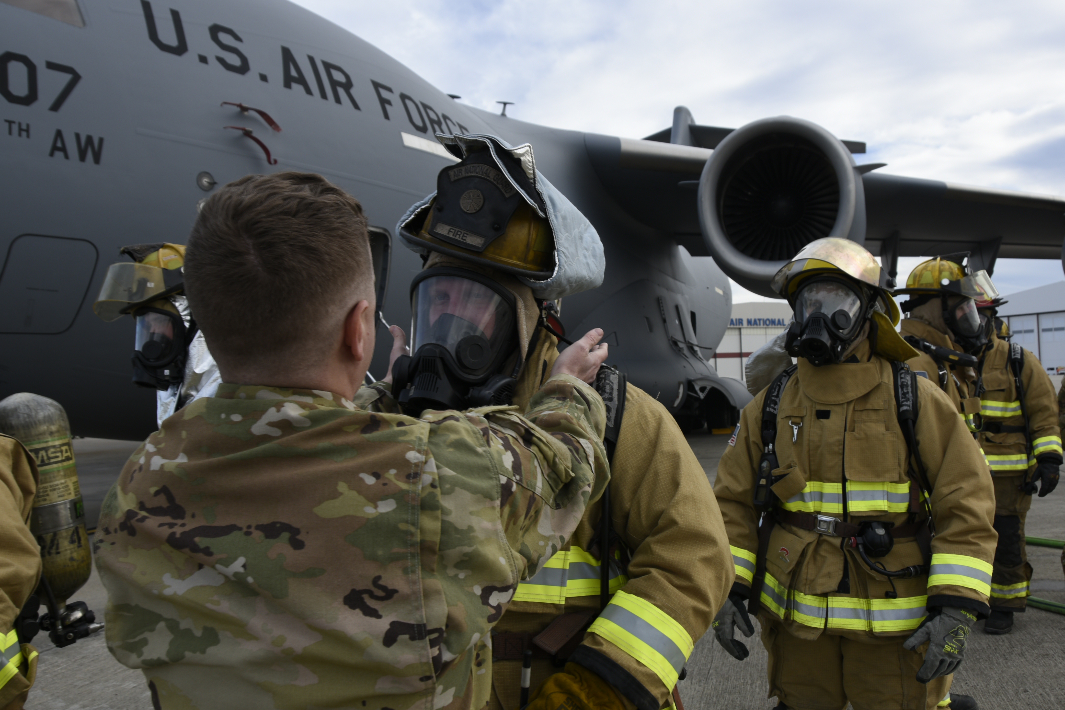 Firefighters line up to assess their uniforms outside the C-17 Globemaster III aircraft
