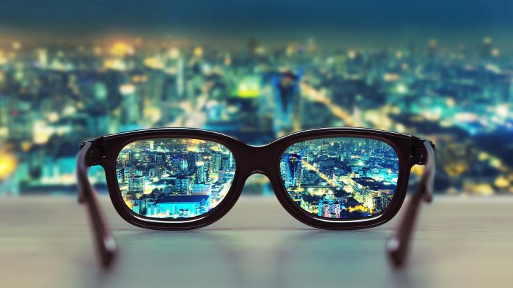 pair of eyeglasses on window ledge with city lights in background