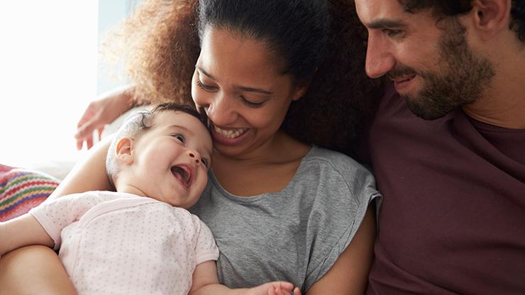 Mother and father looking at laughing baby in mother's arms.
