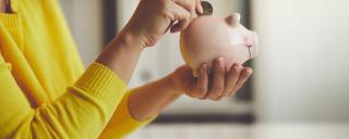 Person putting coins in a piggy bank Person putting coins in a piggy bank