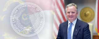 Photo of Treasurer Folwell with flag and seal in the background