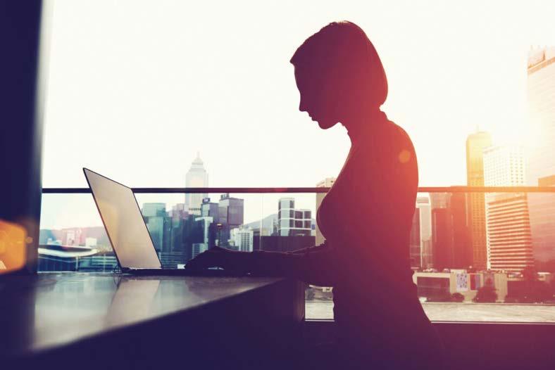 Silhouette of a person using a laptop