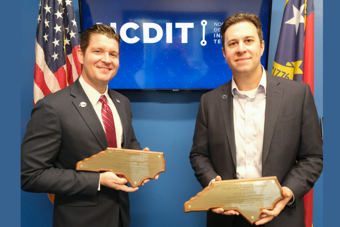 Two men holding plaques and smiling. Screen behind them says NCDIT