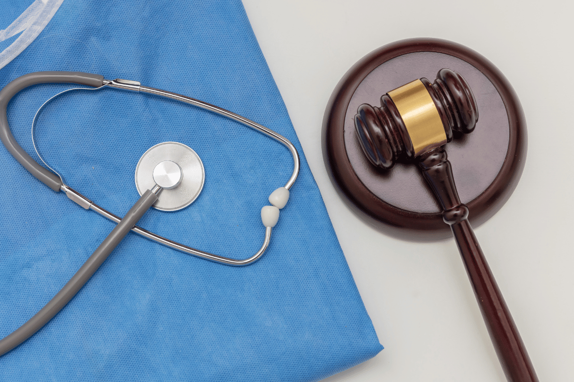 stethoscope lying on blue scrubs next to a gavel