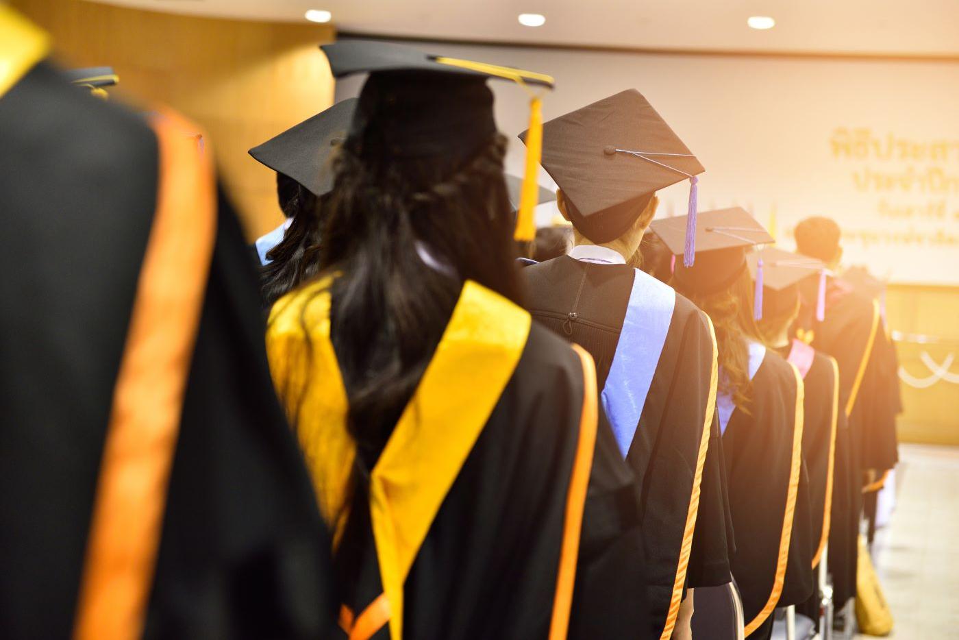Line of graduates in caps and gowns shown from behind. 