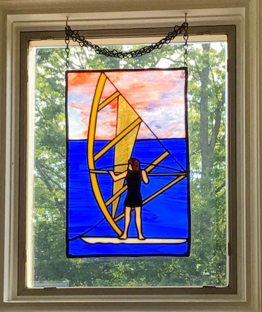 Stained glass window showing a person windsurfing