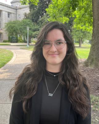 Sophie Clarkson, smiling, facing forward, trees and building in background
