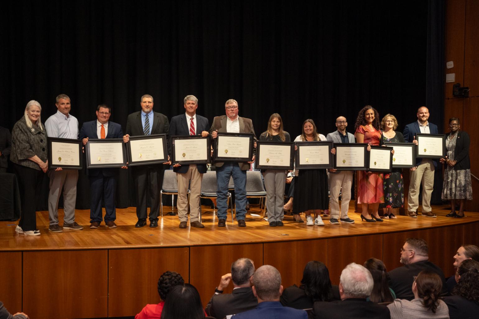 People on stage holding certificates.