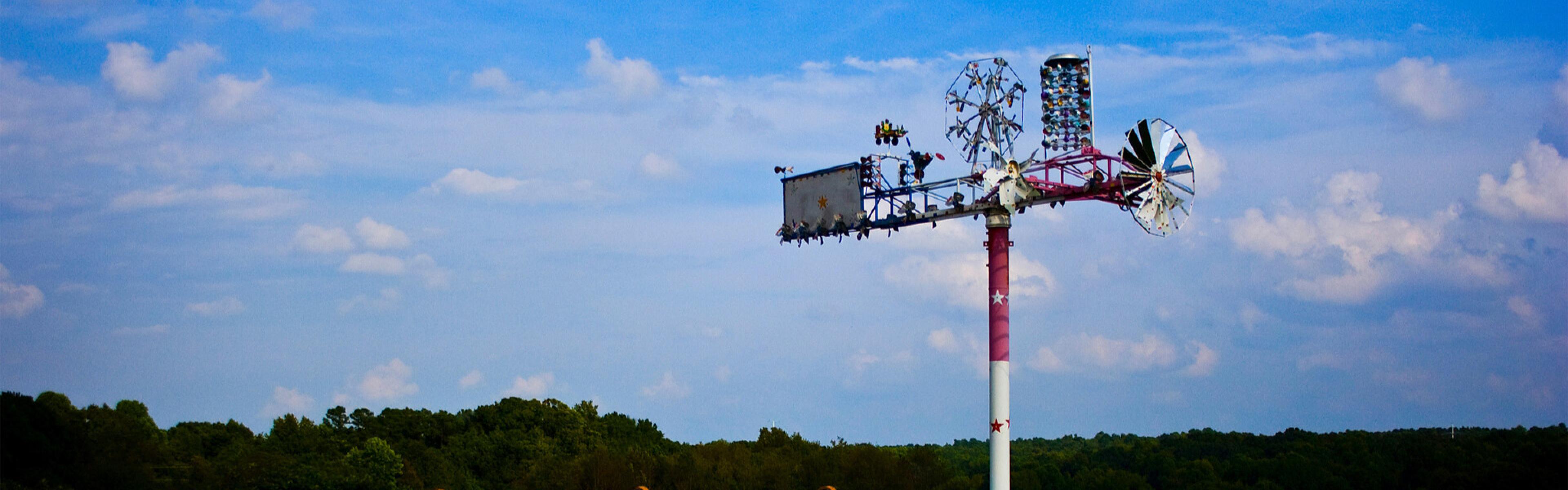 Art installation featuring windmills against a blue sky.