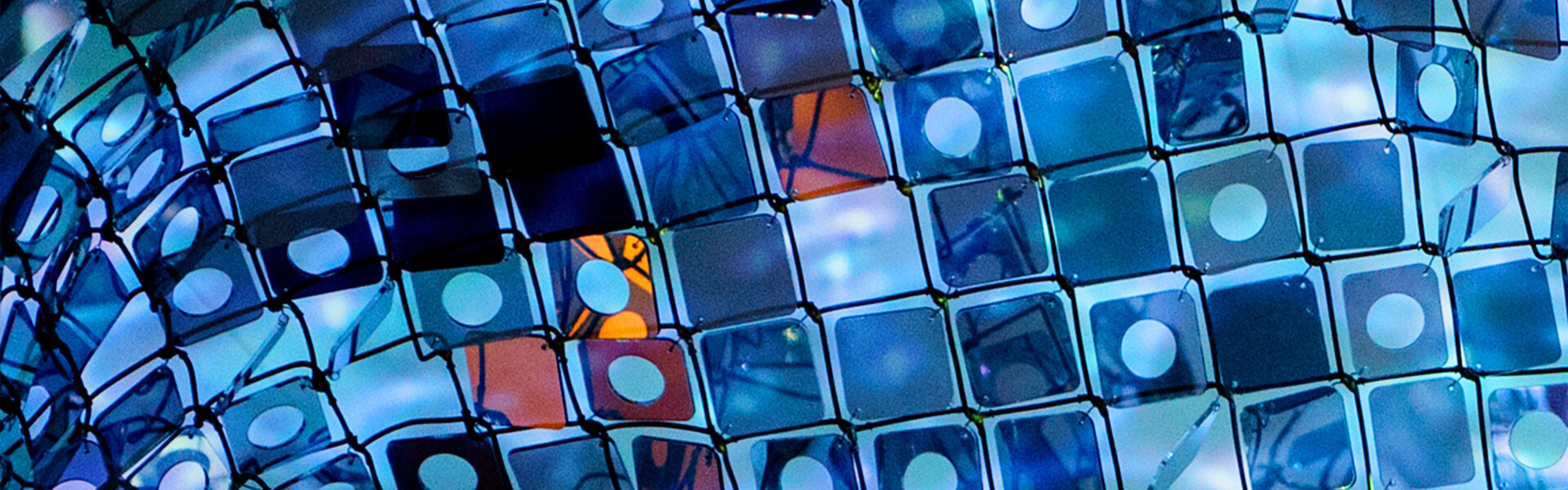 Close-up of art installation featuring a grid of blue tiles against the background of a blue sky.