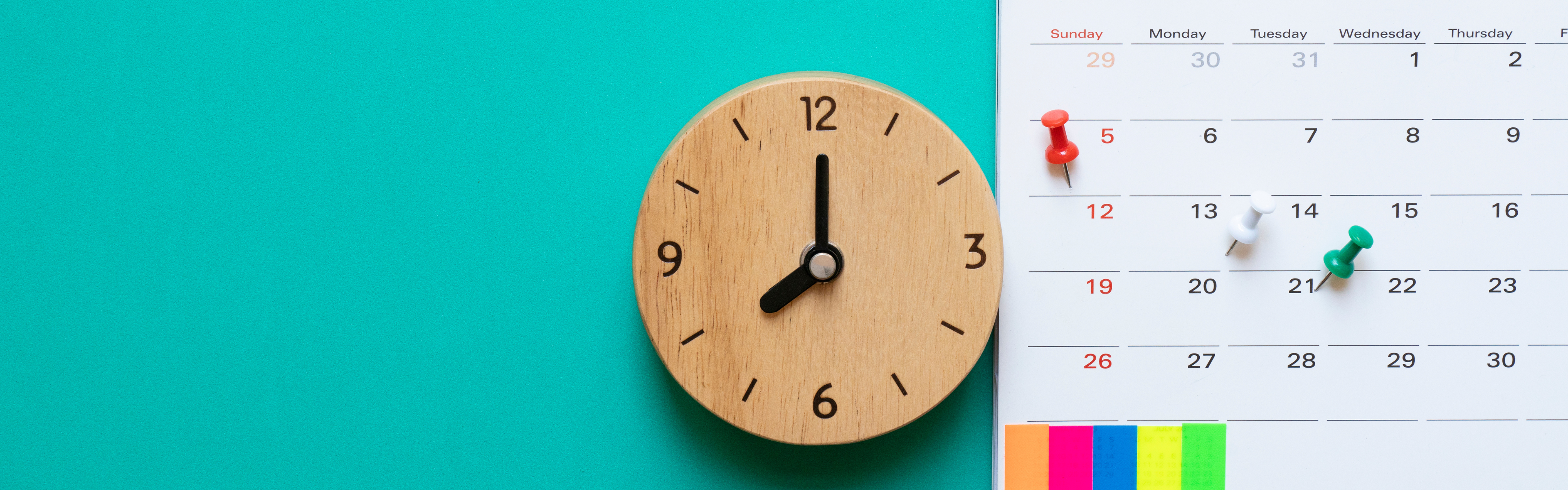 clock next to a calendar with push pins on various dates