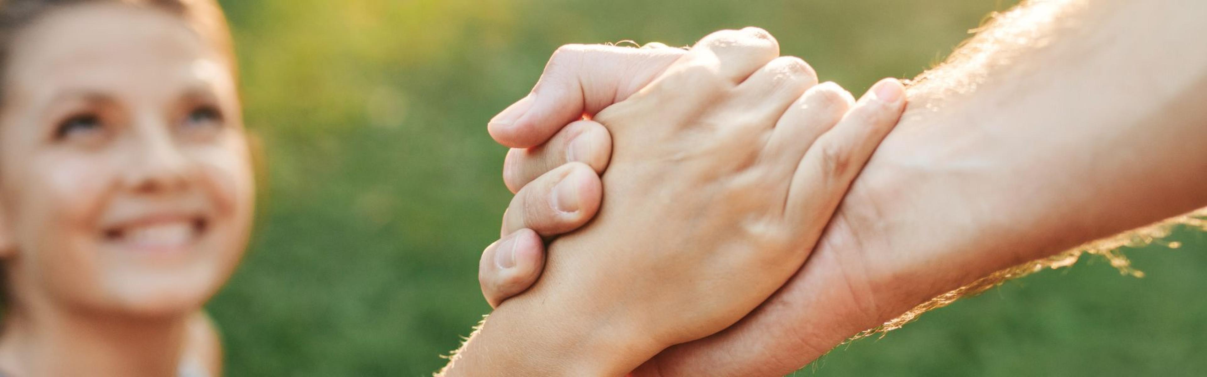 Smiling woman grasps helping hand.