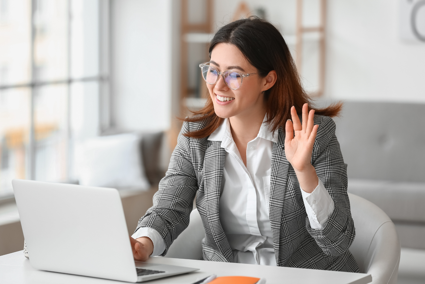 Woman in a virtual interview waving at camera.