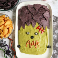 guacamole and blue tortilla chips decorated to look like Frankenstein's head