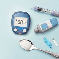 Blood sugar monitor and test strips with a spoonful of sugar next to it.