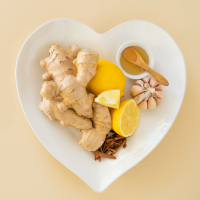 heart-shaped bowl with ginger root, lemon, garlic, and honey in it.