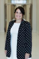 dark haired woman in white dress with a navy polka dotted blazer