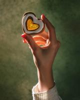 Hand holding a food item in the shape of a heart between the index finger and thumb.