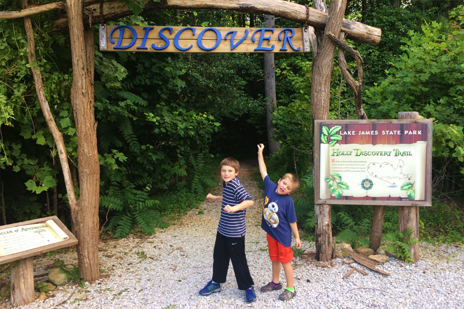 Two kids posing in front of the Holly Discovery Trailhead at Lake James State Park