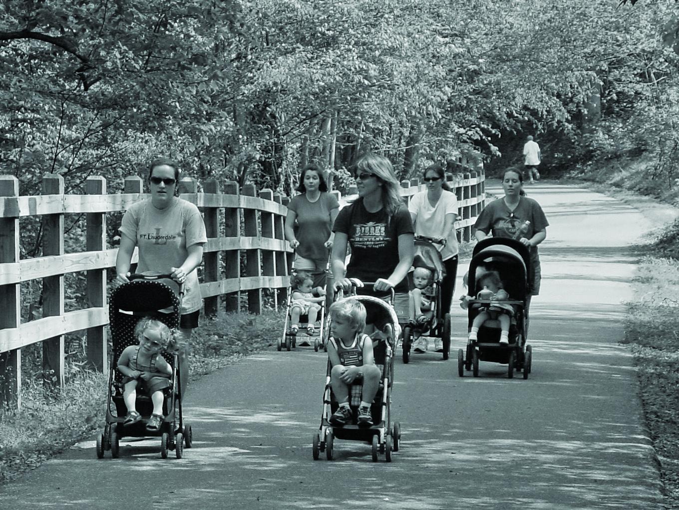 Photo of families pushing strollers on a paved trail