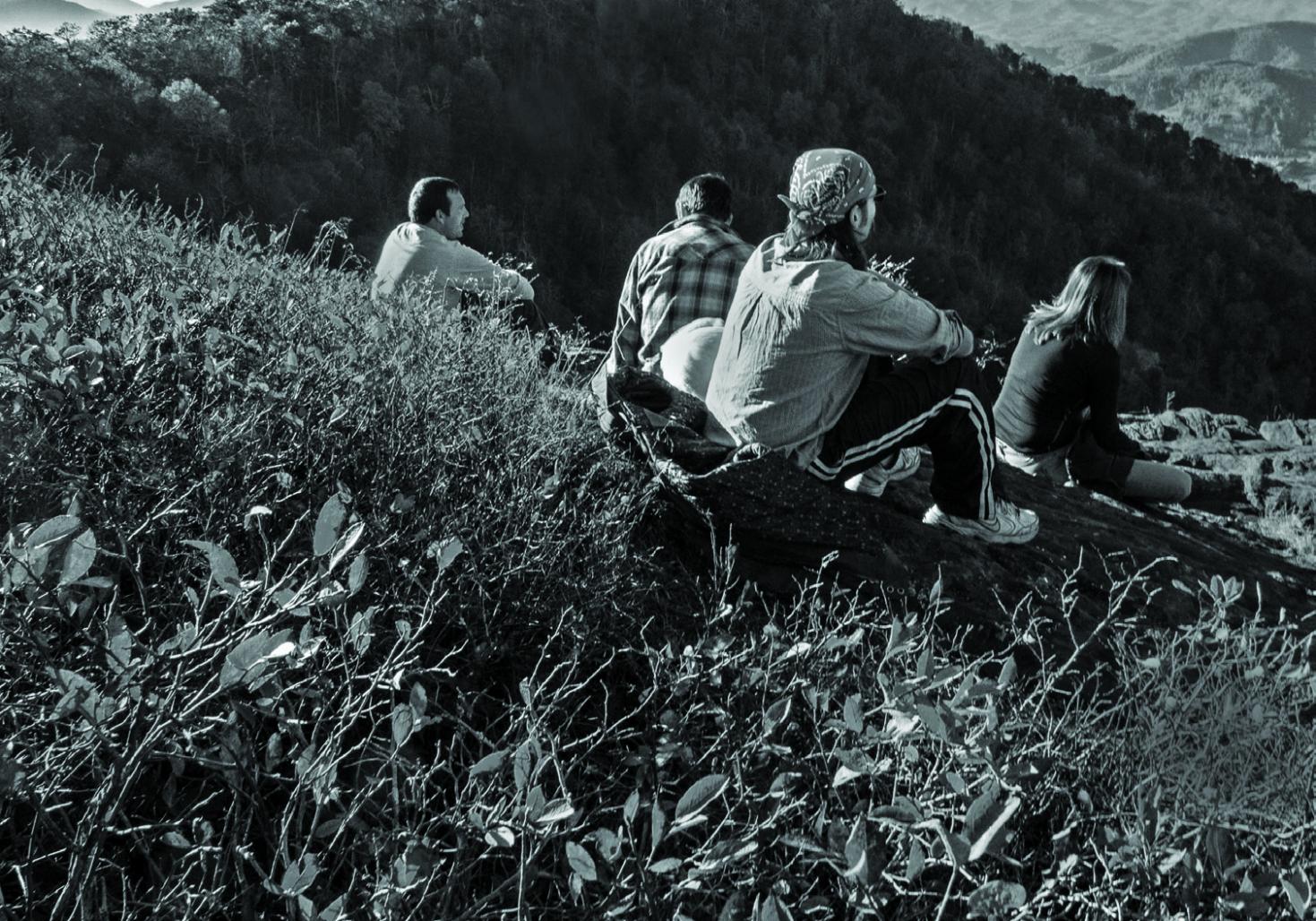 Photo of people sitting on a grassy hill