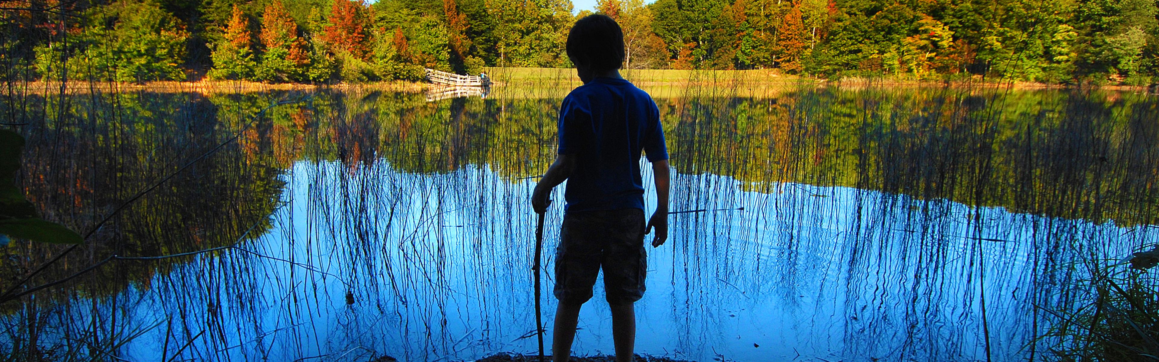 A boy stands at the shore of the lake at Crowders Mountain State Park