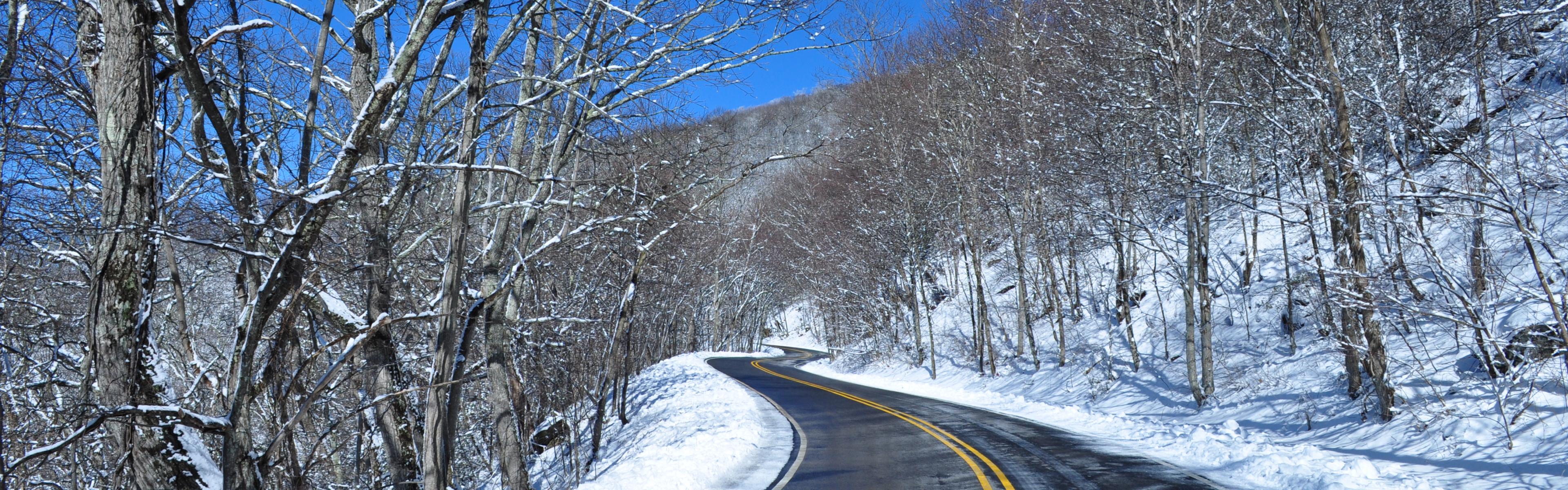 A road winds through the snow on a clear day
