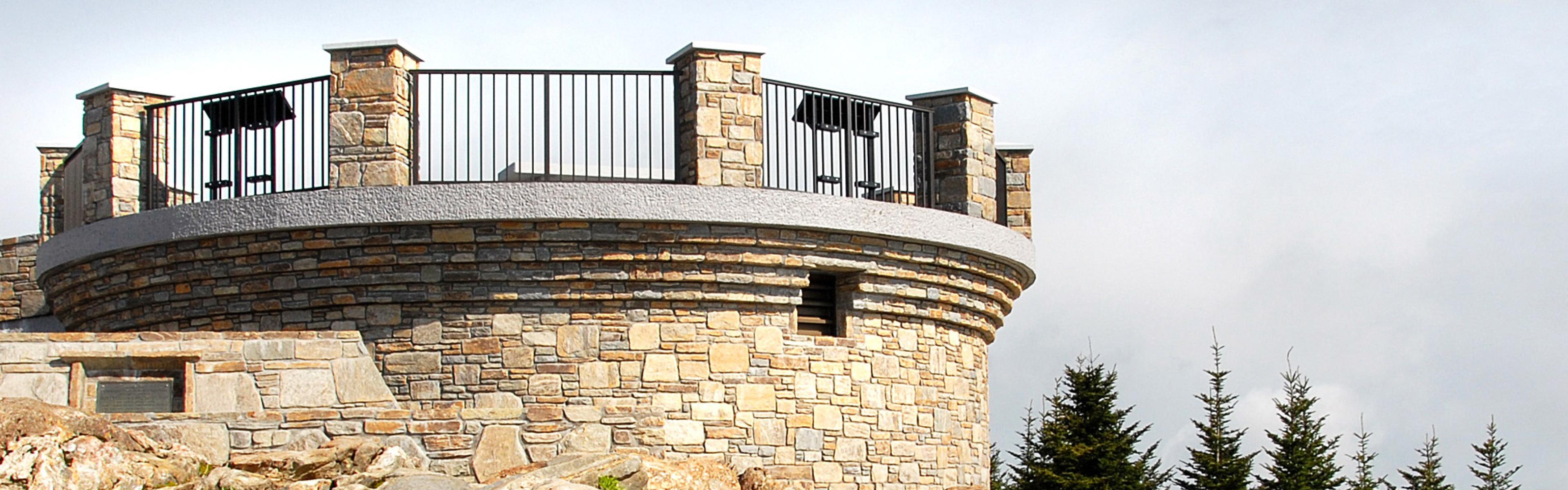 The summit observation deck on a partly cloudy day with rock outcroppings in the foreground