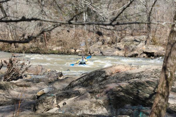a person kayaking a river surrounded by rocky outcroppings