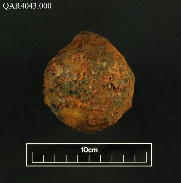 A round, concreted hand grenade artifact with a 10cm scale bar