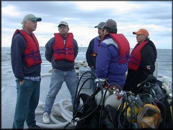 Divers sitting on the edge of a boat preparing to dive
