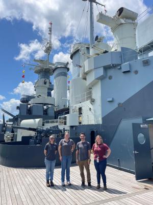 QAR Lab staff standing in front of the battleship